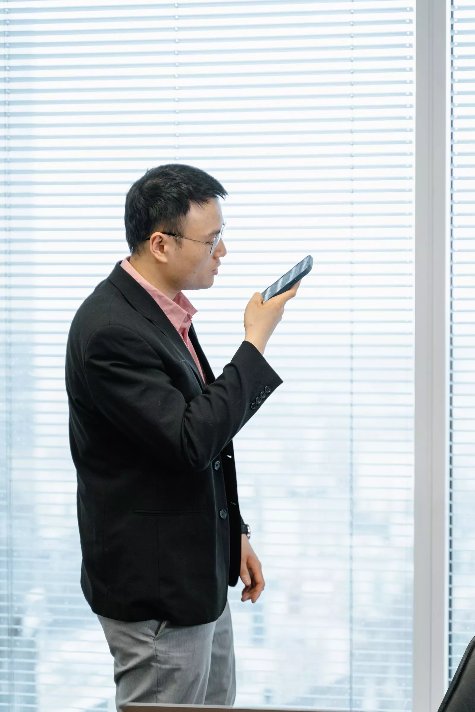 Man spreekt een spraakbericht in op zijn smartphone op kantoor in plaats van te typen