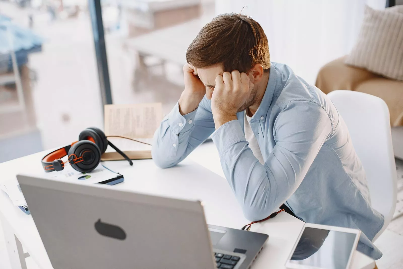 Gefrustreerde ondernemer in zijn thuiskantoor kijkt naar zijn laptopscherm terwijl hij zelf aan zijn website werkt