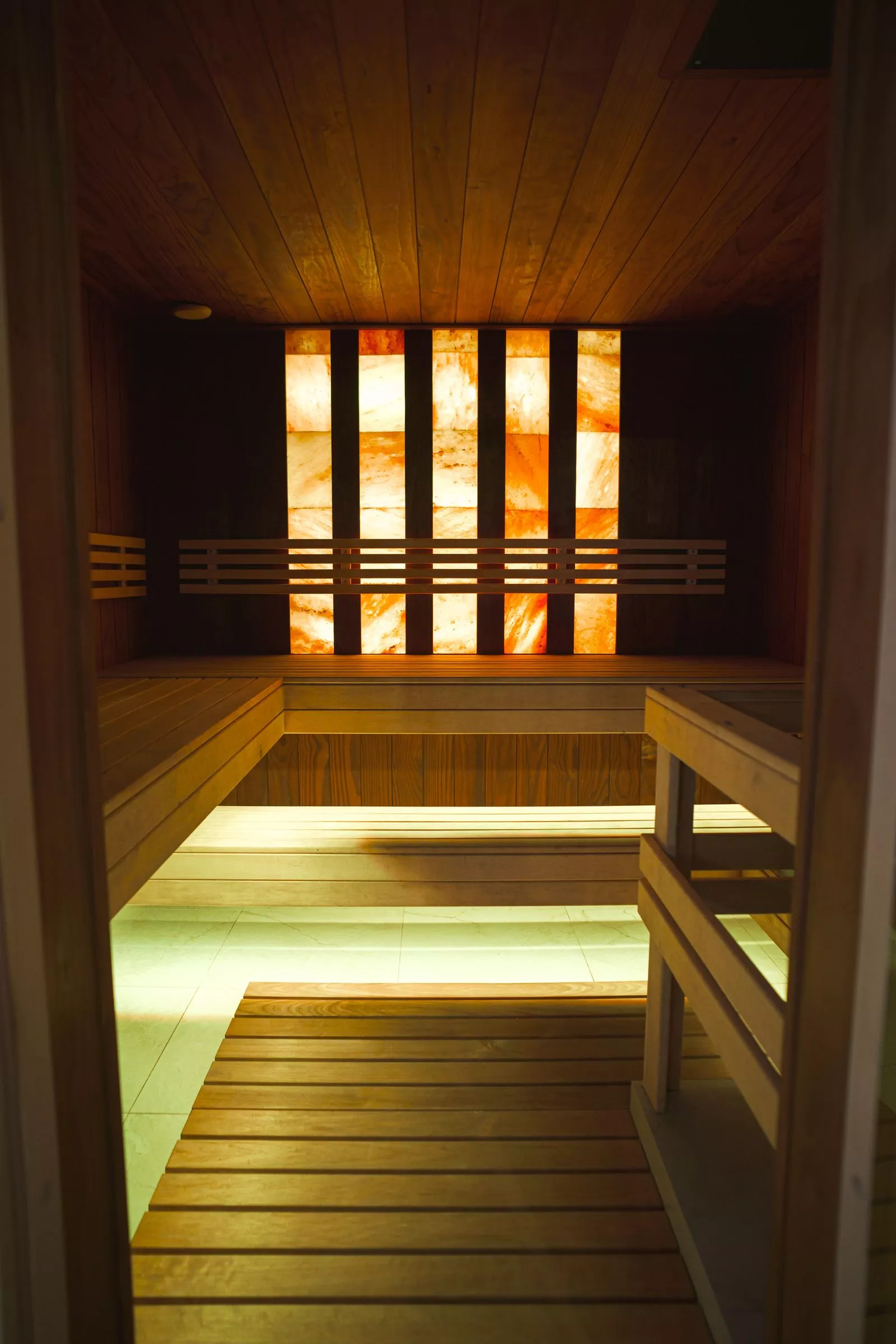 Modern sauna-interieur met warme houten panelen en een verlichte zoutwand