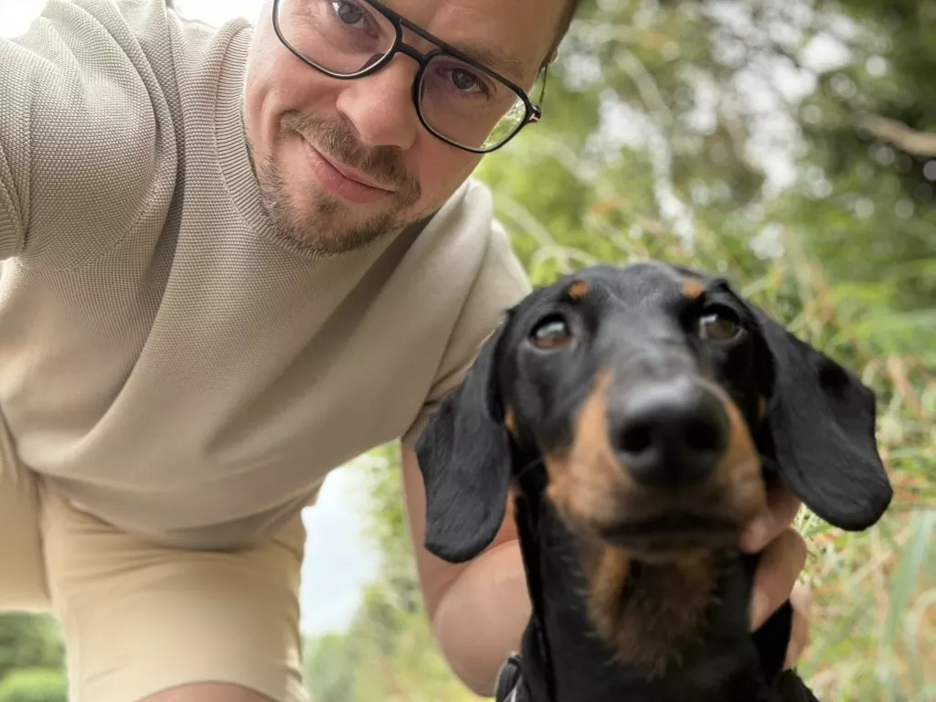 Pieter wandelt met zijn hond in een zonnig park, terwijl hij onderweg inspiratie voor een blog opdoet